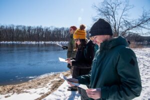 Students reading handout and looking at river in winter