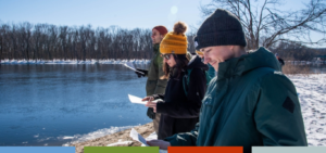 Students reading handout and looking at river in winter