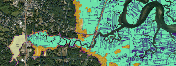 marsh+migration+image+from+GBNERR A river over tops its banks and flows by an old mill building.