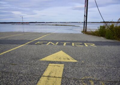 A road with an arrow and enter sign painted on pointing to a flooded section