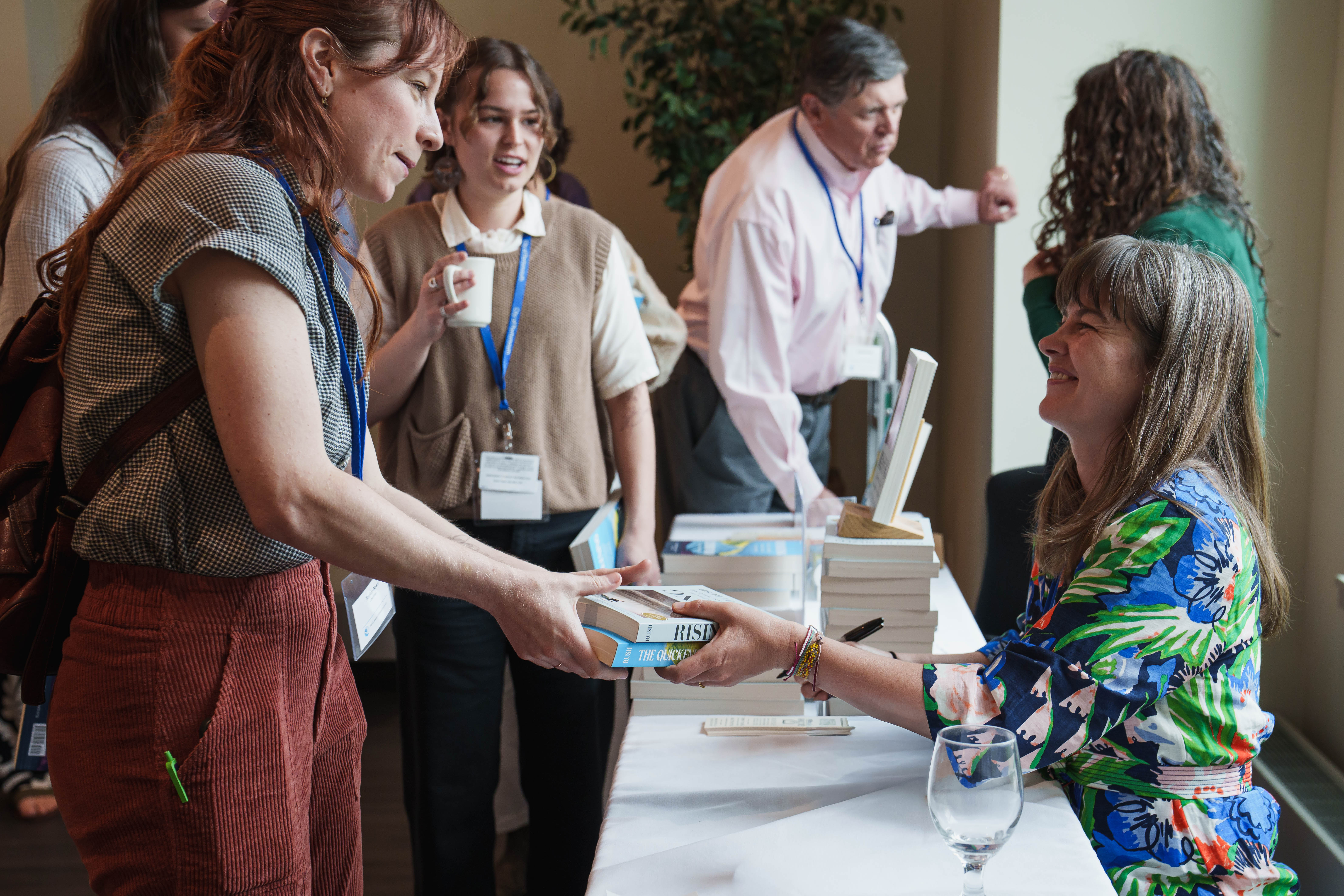 Elizabeth Rush hands a book to a visitor at a book signing table.