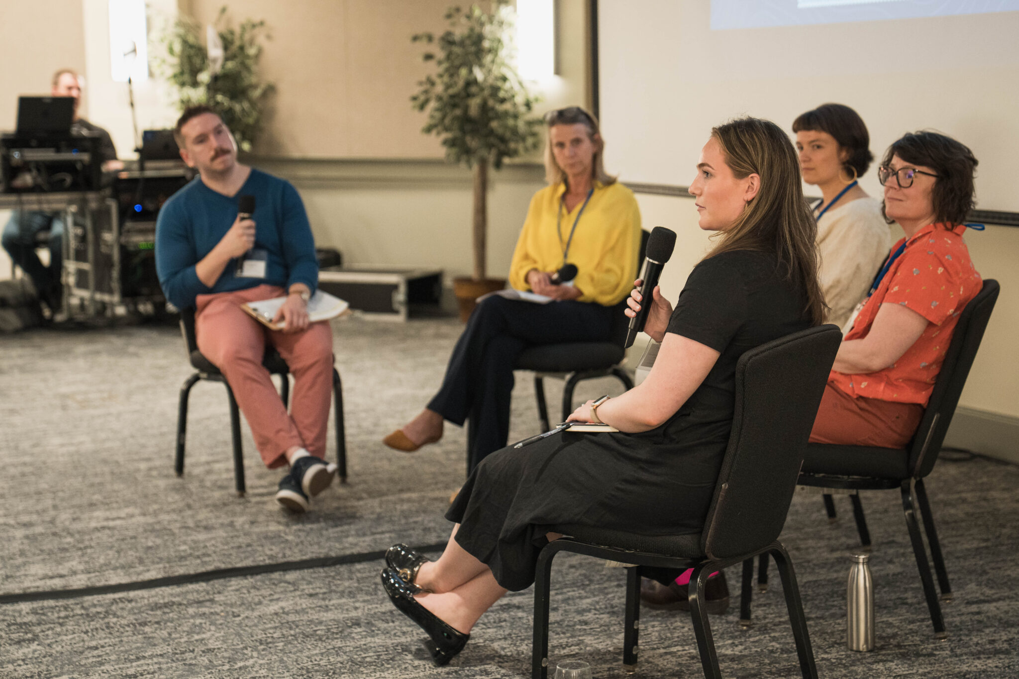 Five people sit in a half circle for a panel at a conference.